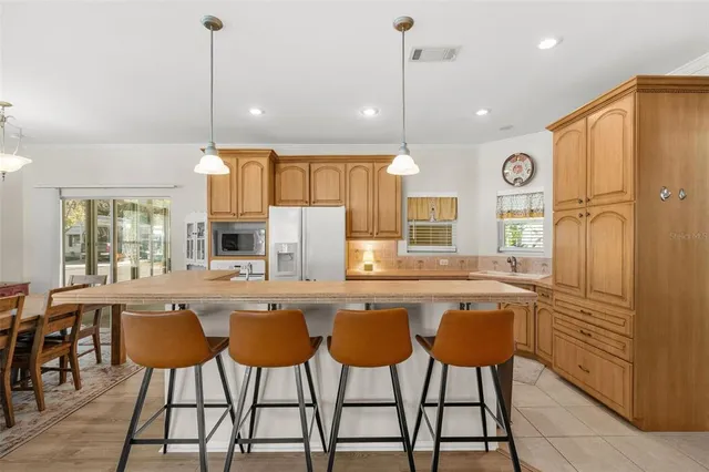 a kitchen with stainless steel appliances granite countertop a dining table chairs and white cabinets