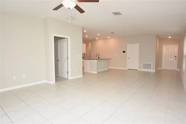 an empty room with kitchen and ceiling fan