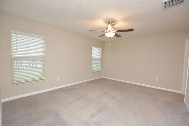an empty room with a window and a ceiling fan