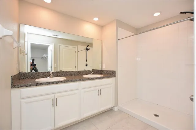 a bathroom with a granite countertop sink a mirror and a shower