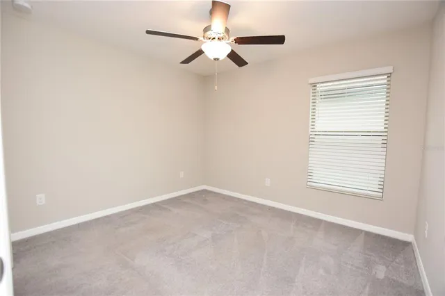 an empty room with a window and a fan