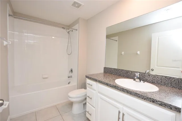 a bathroom with a granite countertop sink a toilet a mirror and shower