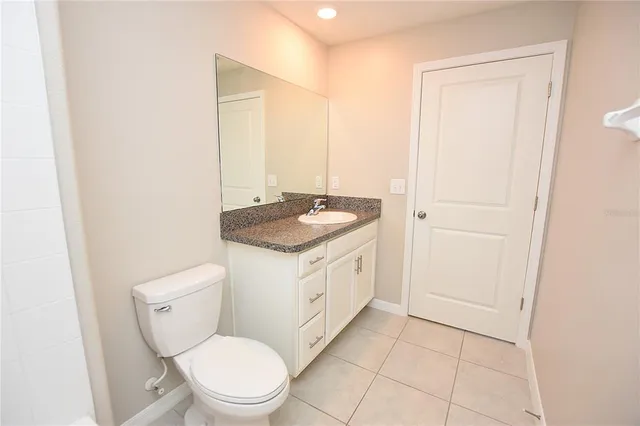 a bathroom with a granite countertop toilet a sink and a mirror