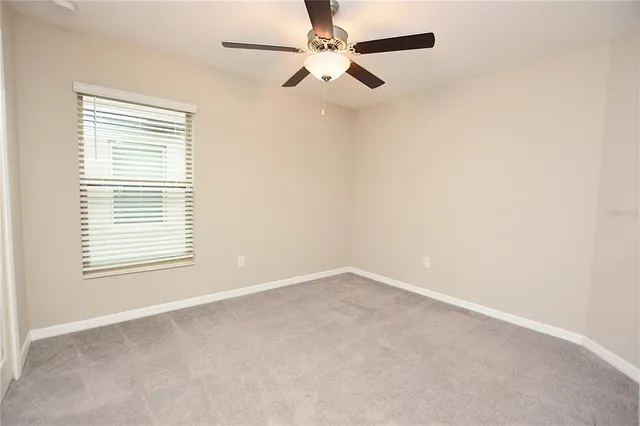 an empty room with a window and a fan