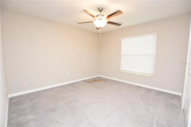an empty room with a window and a ceiling fan