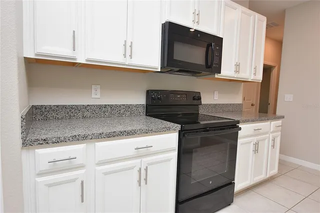 a kitchen with granite countertop white cabinets and a stove top oven