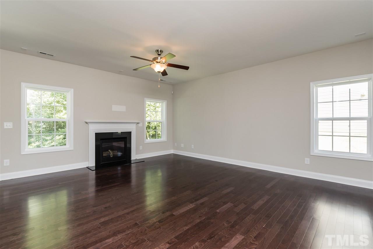 3413 Grosbeak Way Raleigh, NC 27616 - Photo 8 of 25 an empty room with wooden floor fireplace and windows