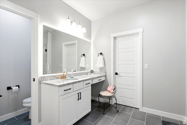 3049 South 2675 West Syracuse, UT 84075 - Photo 17 of 37 White vanity with a light-colored countertop, gold-finish faucet, and a large illuminated mirror
