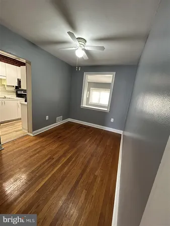 an empty room with wooden floor cabinet and windows