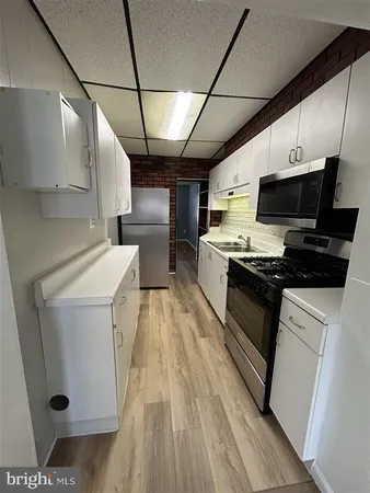a kitchen with stainless steel appliances a stove a sink and white cabinets
