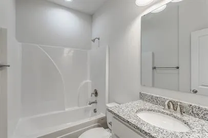 a bathroom with a granite countertop sink a toilet and shower