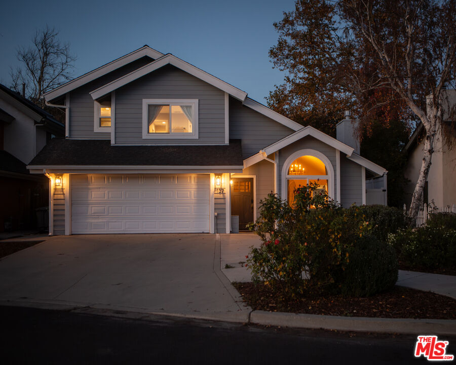 a view of a house with a yard plants and large tree