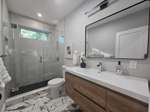 a bathroom with a sink a toilet and shower