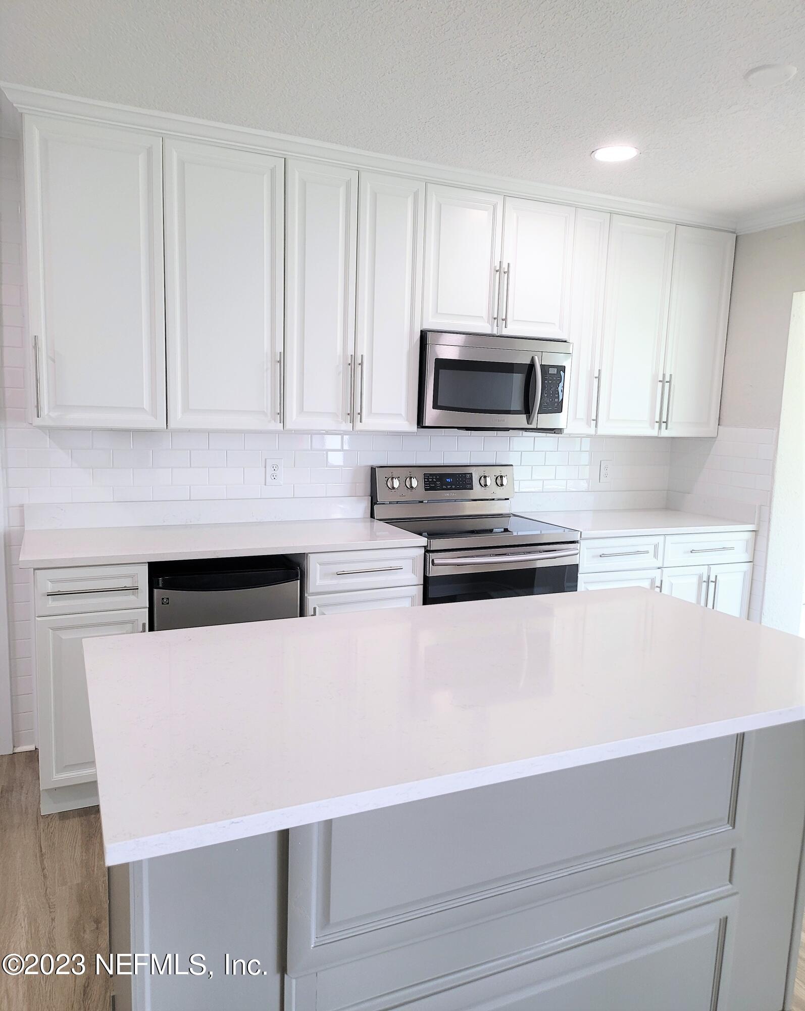 2627 Adele Road Jacksonville, FL 32216 - Photo 11 of 27 a kitchen with stainless steel appliances a stove a microwave and white cabinets