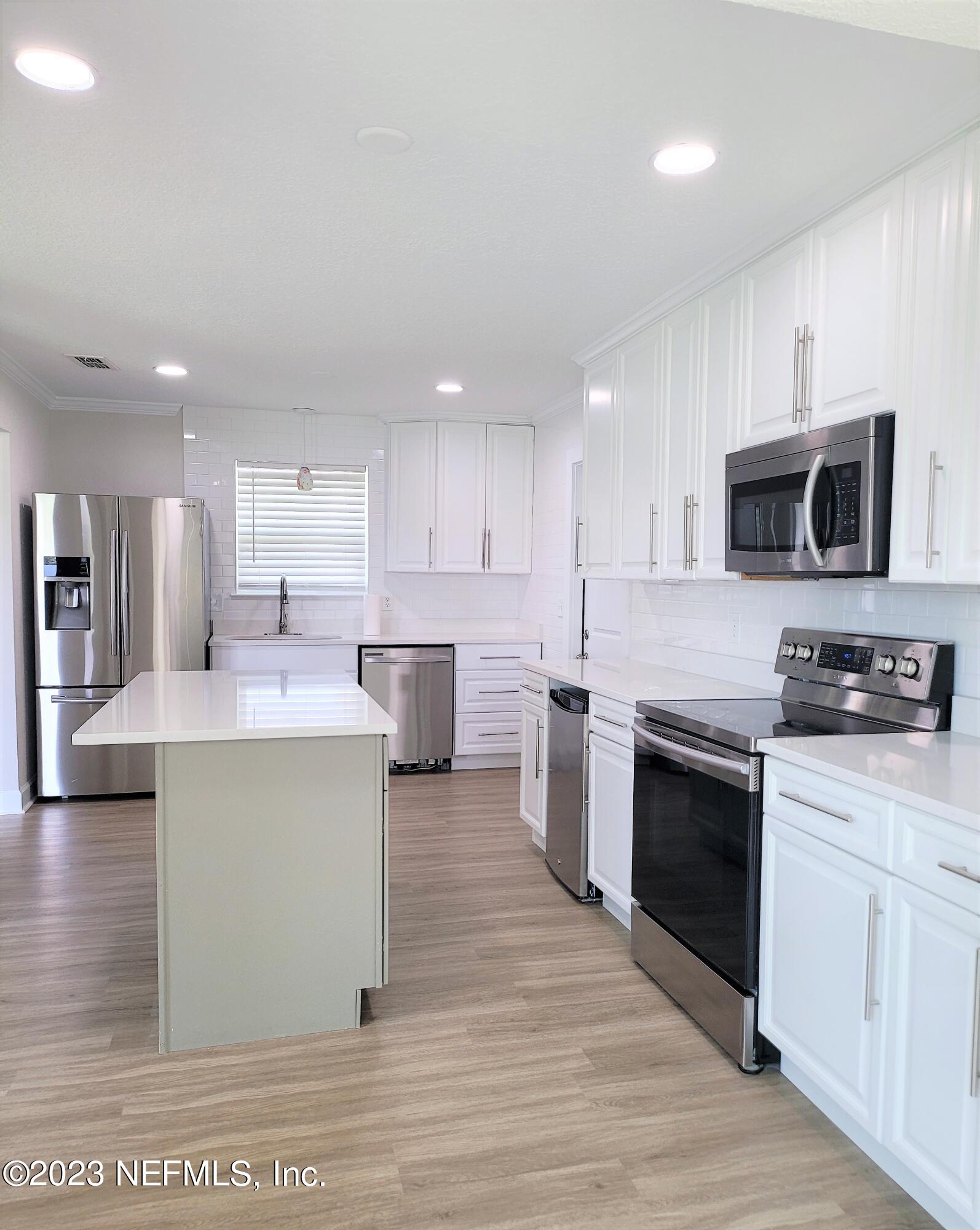 2627 Adele Road Jacksonville, FL 32216 - Photo 10 of 27 a kitchen with stainless steel appliances kitchen island granite countertop a stove a sink and a microwave