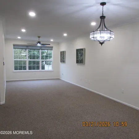 a view of a livingroom with a chandelier wooden floor and windows