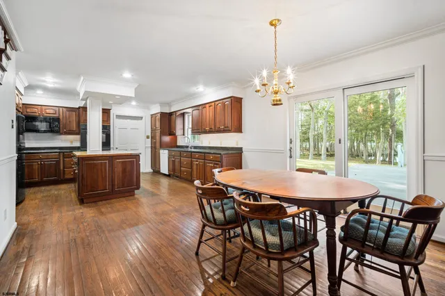 a kitchen with stainless steel appliances a dining table chairs and refrigerator