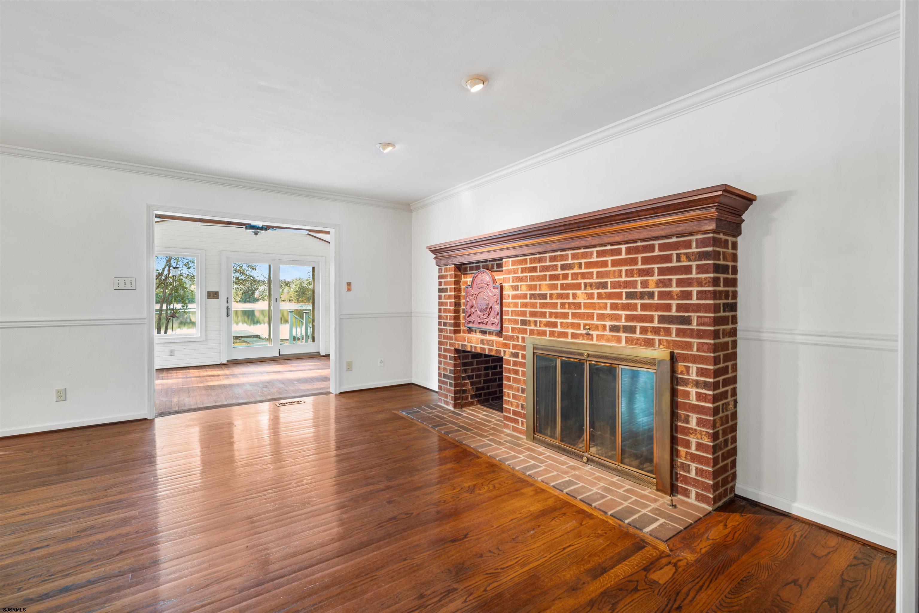 216 Riverside Drive Port Republic, NJ 08241 - Photo 9 of 47 an empty room with wooden floor fireplace and windows