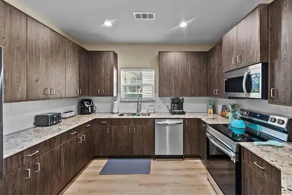 a kitchen with stainless steel appliances granite countertop wooden cabinets a sink dishwasher a stove and a refrigerator