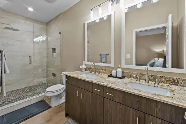 a bathroom with a granite countertop sink a toilet a mirror and shower
