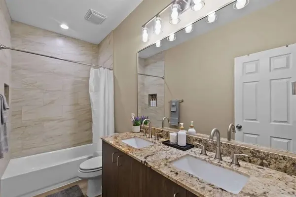 a bathroom with a granite countertop sink a toilet and bathtub