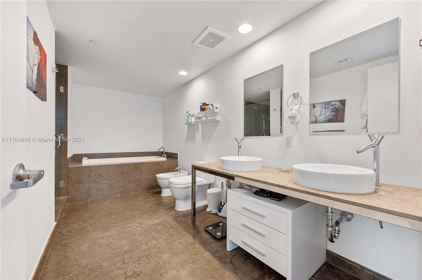 465 Brickell Avenue, Unit 2702 Miami, FL 33131 - Photo 21 of 37 a spacious bathroom with a sink a toilet and a mirror