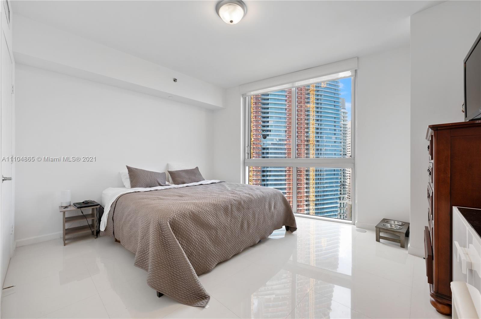 465 Brickell Avenue, Unit 2702 Miami, FL 33131 - Photo 32 of 37 a bedroom with a bed dresser and a window