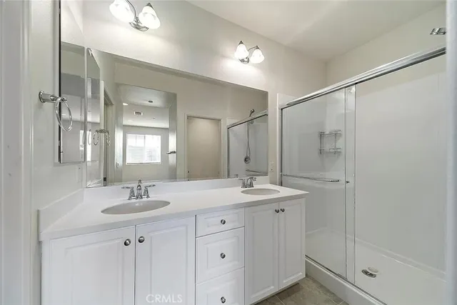 a bathroom with a double vanity sink mirror and shower