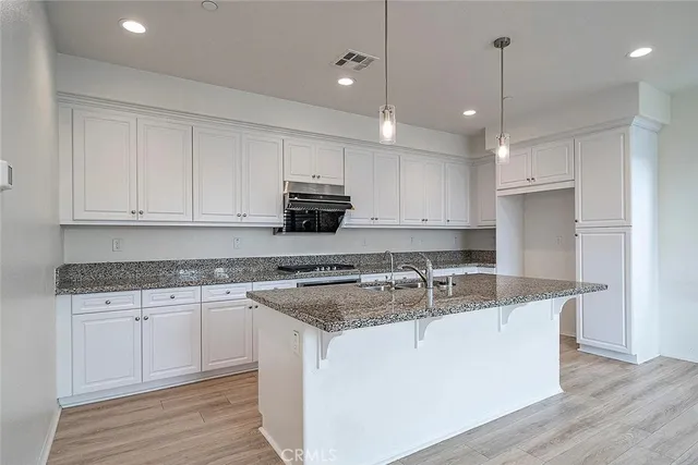 a kitchen with kitchen island granite countertop a sink a counter space stainless steel appliances and cabinets