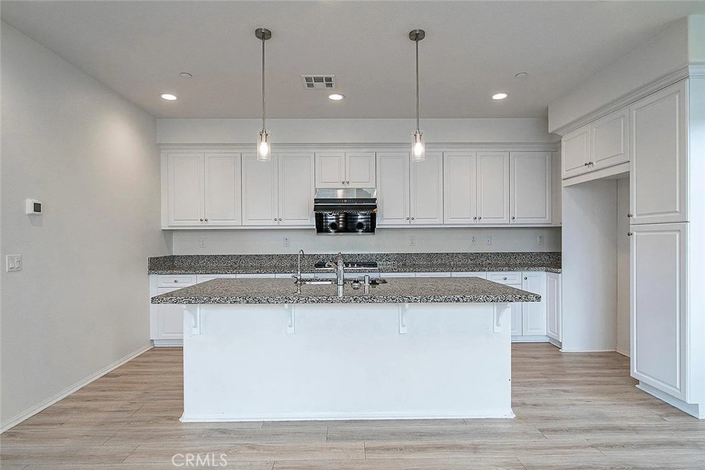 7364 Solstice Place Rancho Cucamonga, CA 91739 - Photo 6 of 19 a kitchen with kitchen island stainless steel appliances granite countertop a sink a stove and a wooden floors
