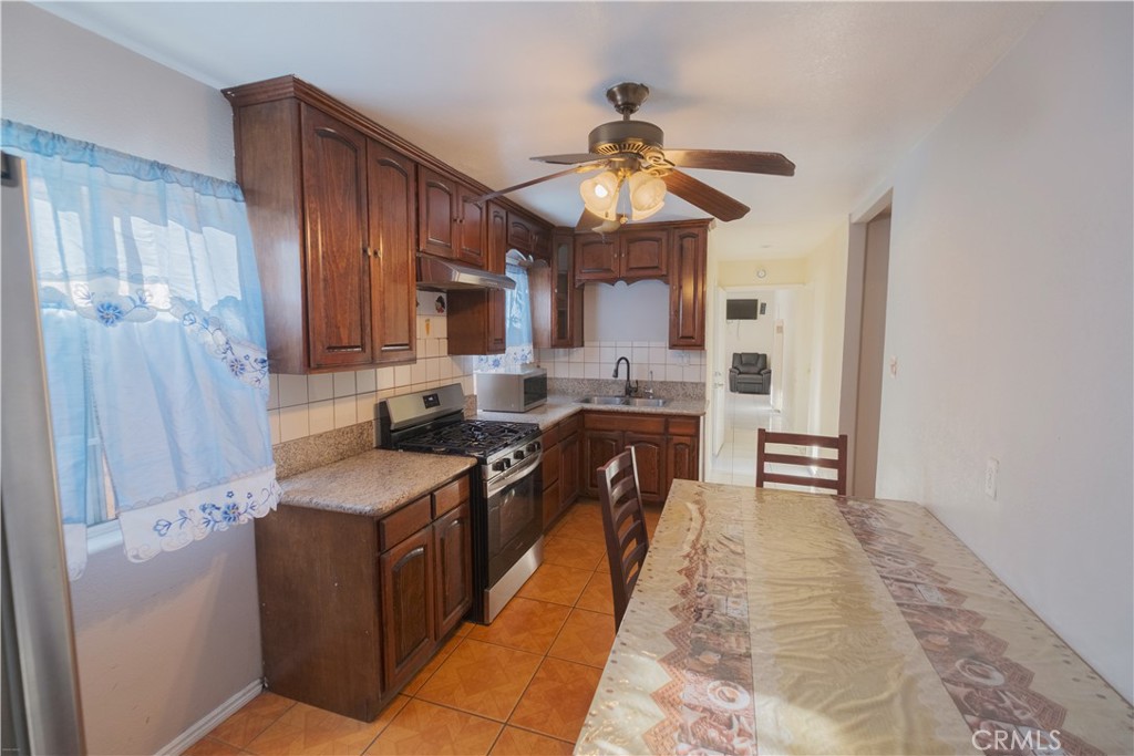 2534 East 127th Street Compton, CA 90222 - Photo 4 of 22 a kitchen with stainless steel appliances granite countertop a stove a sink dishwasher and a refrigerator with wooden floor