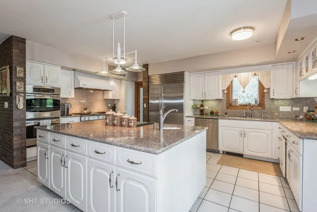 a kitchen with kitchen island granite countertop a sink cabinets and window
