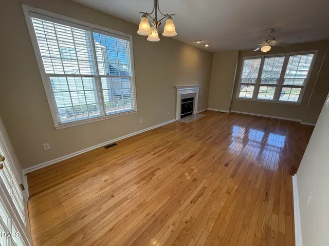 a view of an empty room with window and wooden floor