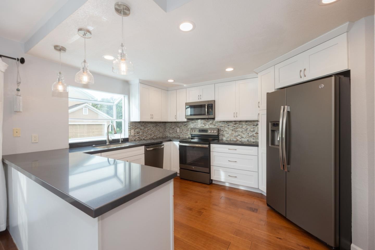 9 Merion Road Half Moon Bay, CA 94019 - Photo 6 of 14 a kitchen with stainless steel appliances granite countertop a refrigerator a sink dishwasher a stove and white countertops with wooden floor