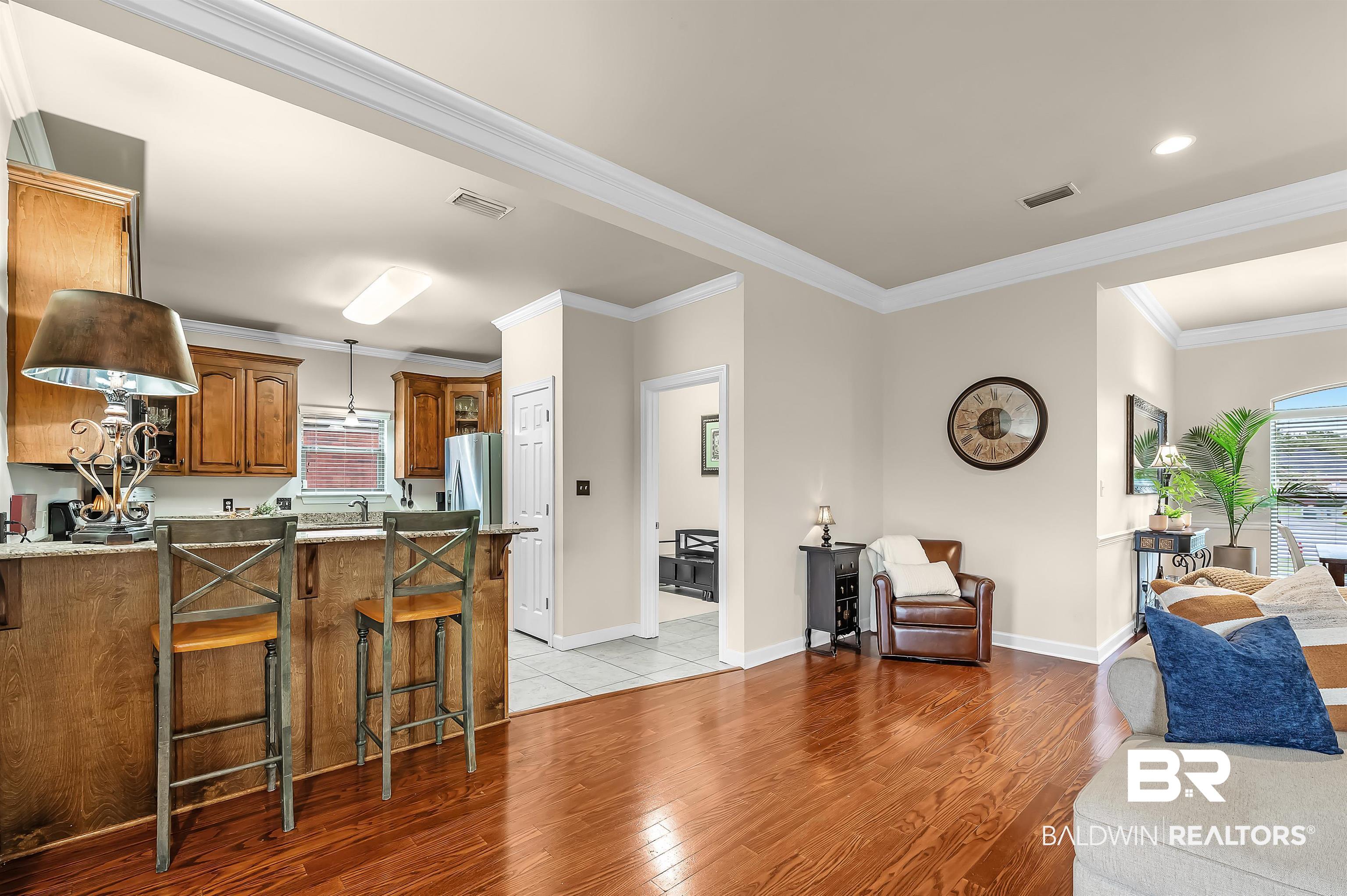 9376 Sable Court Daphne, AL 36526 - Photo 22 of 46 Kitchen with light wood-type flooring, stainless steel refrigerator with ice dispenser, ornamental molding, and a kitchen breakfast bar