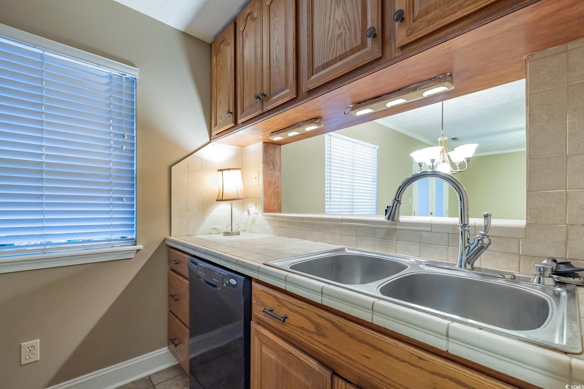 620 15th Avenue South, Unit 89 Surfside Beach, SC 29575 - Photo 3 of 14 Kitchen with brown cabinets, tile countertops, dishwasher, light tile patterned flooring, and tasteful backsplash