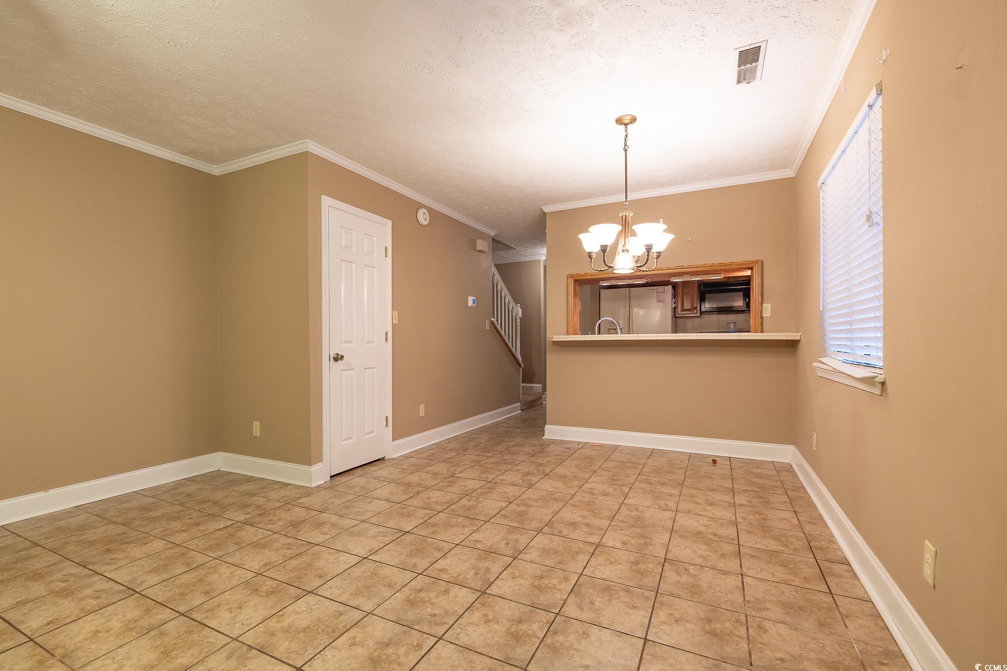 620 15th Avenue South, Unit 89 Surfside Beach, SC 29575 - Photo 5 of 14 Spare room with crown molding, light tile patterned flooring, a textured ceiling, stairway, and a chandelier