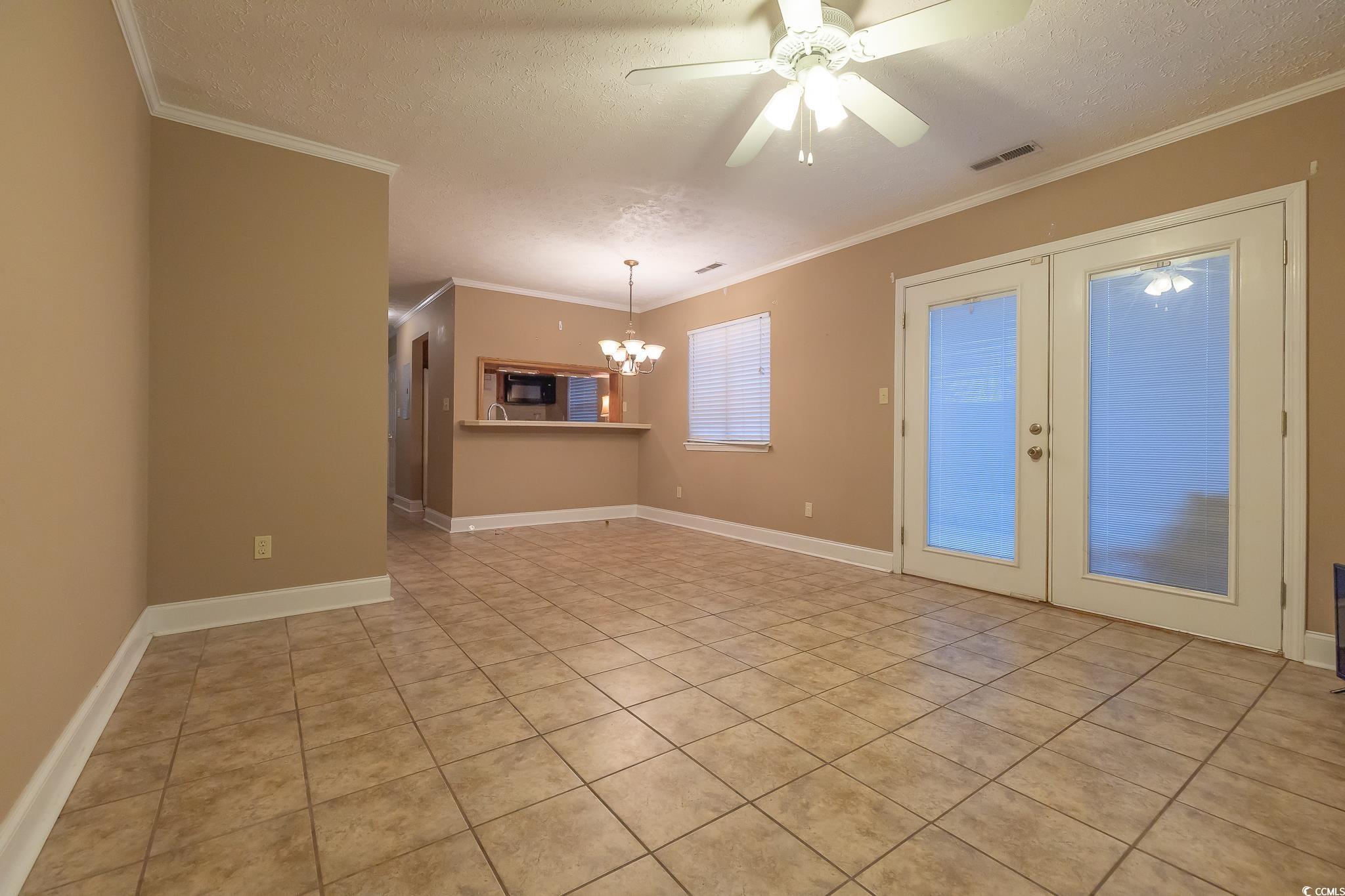 620 15th Avenue South, Unit 89 Surfside Beach, SC 29575 - Photo 8 of 14 Empty room with a textured ceiling, light tile patterned floors, a ceiling fan, ornamental molding, and french doors