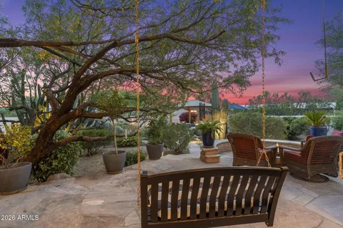 a view of a patio with couches table and chairs under an umbrella with a fire pit