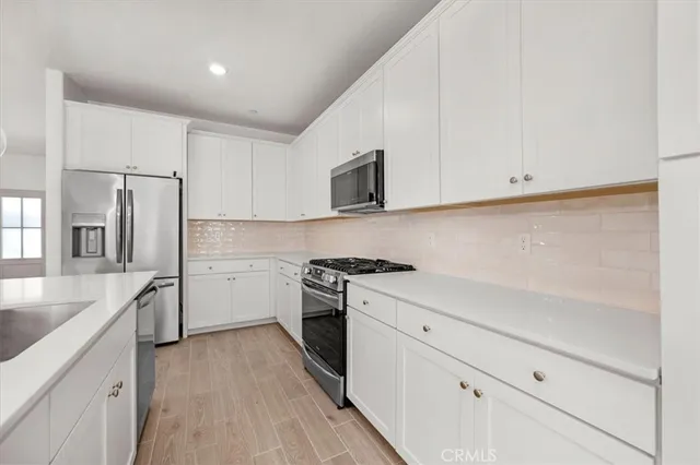 a kitchen with stainless steel appliances granite countertop a sink a stove and a refrigerator