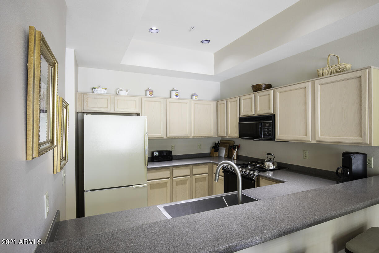 8270 North Hayden Road, Unit 2019 Scottsdale, AZ 85258 - Photo 14 of 39 a kitchen with stainless steel appliances a refrigerator a sink a stove a microwave and wooden cabinets