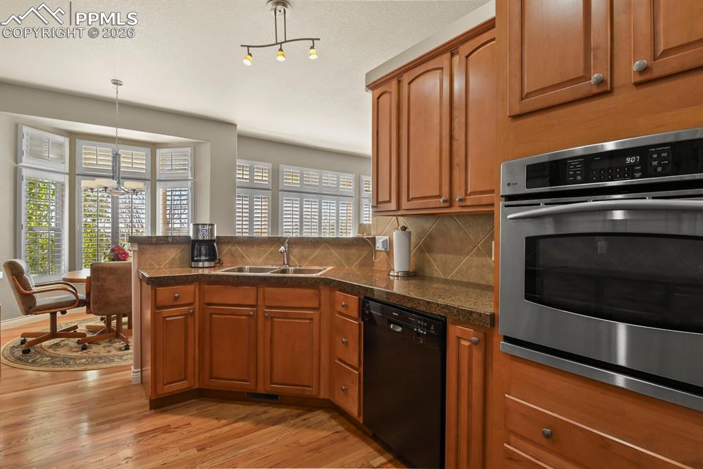 617 Concerto Drive Colorado Springs, CO 80906 - Photo 9 of 46 The kitchen features wood cabinetry, a built-in oven, double stainless steel sinks and a dishwasher, with hardwood floors extending into an eating area