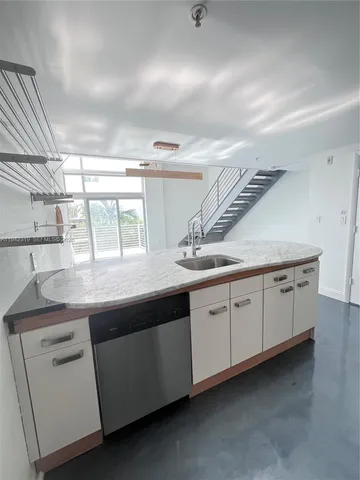 a kitchen with granite countertop a sink and dishwasher a stove with wooden floors