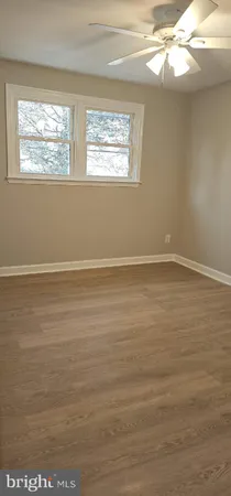 a view of an empty room with wooden floor and windows