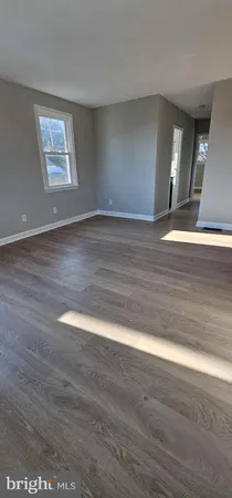 a view of an empty room with wooden floor and window
