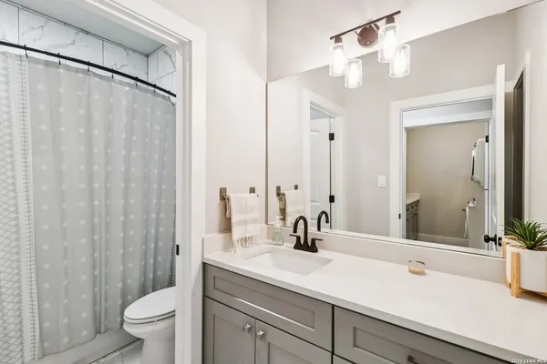 a bathroom with a sink a toilet and shower curtain