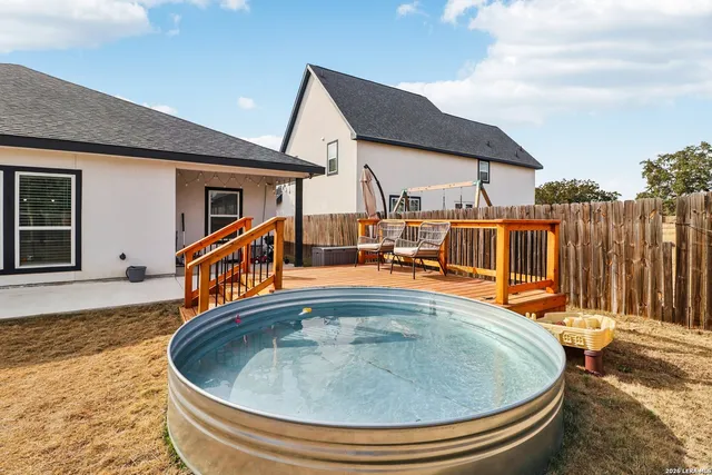 a view of small house with swimming pool and wooden fence