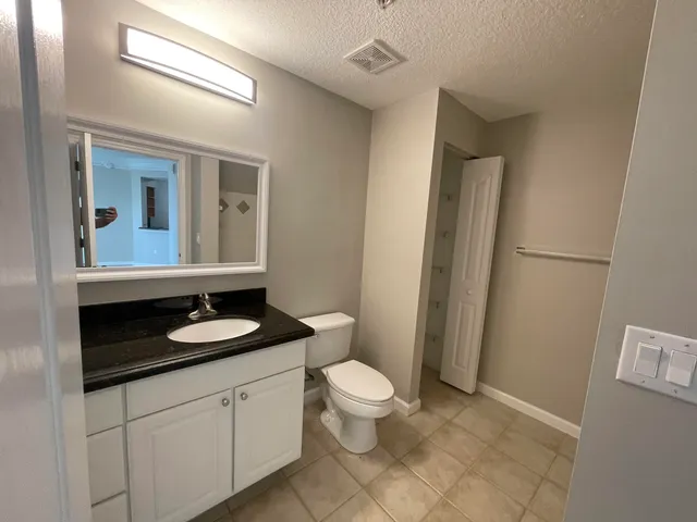 a bathroom with a granite countertop sink a toilet a mirror and shower