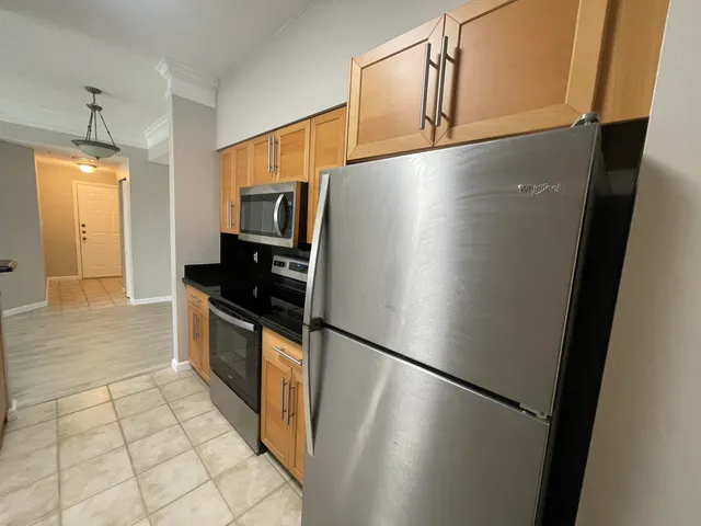 a view of a refrigerator in kitchen and an empty room with wooden floor