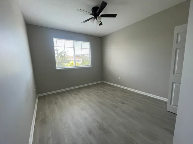 an empty room with windows and fan